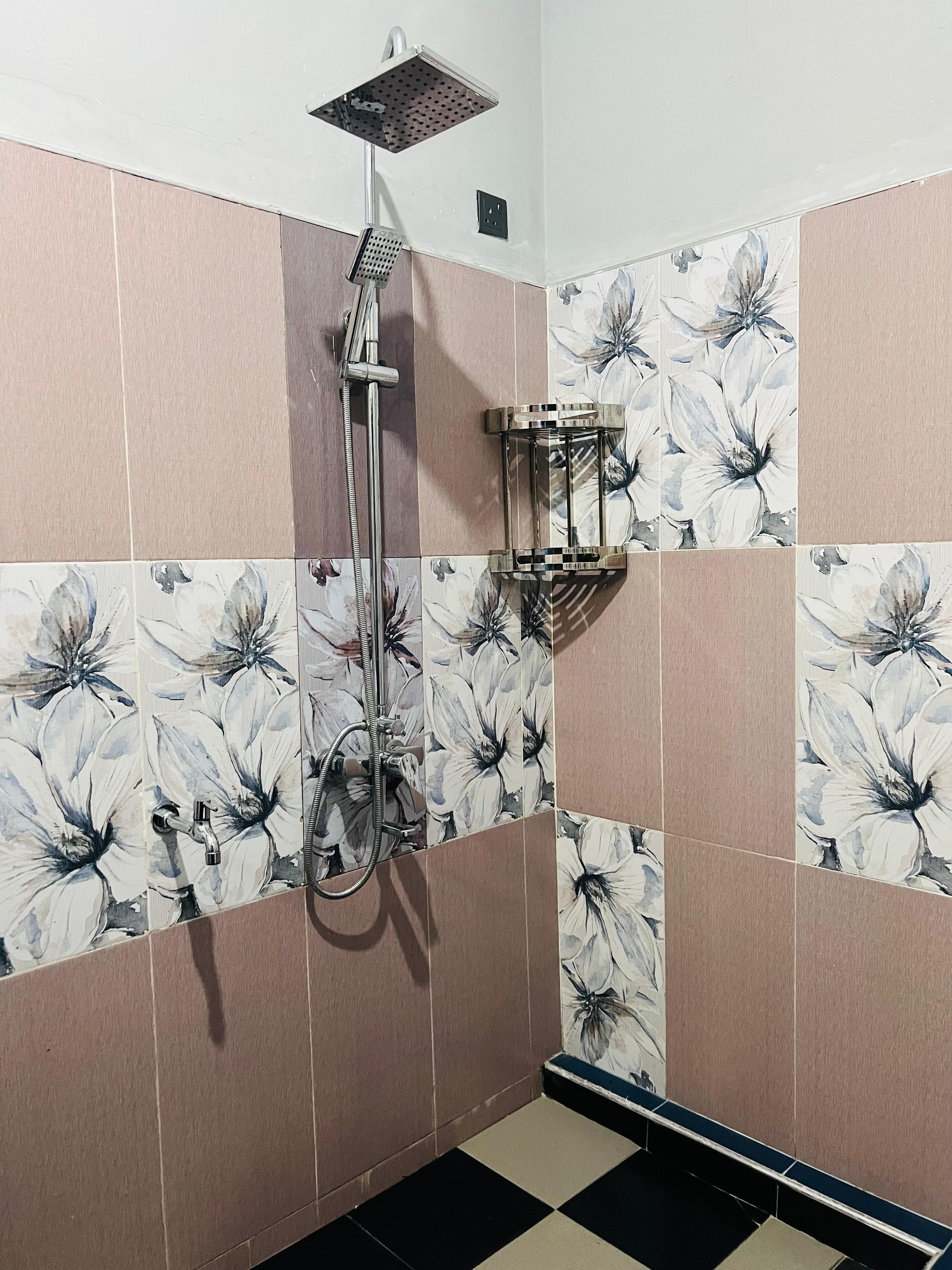 Rain shower and handheld shower against floral bathroom tiles