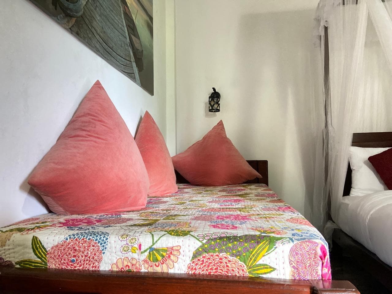 Floral daybed with coral cushions beside the Hidden Heaven canopy bed