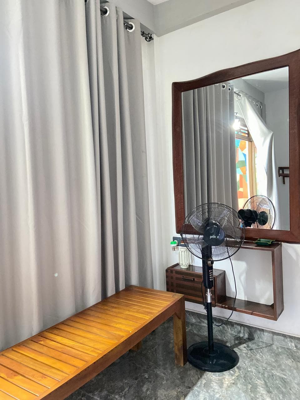 Dressing corner with a wooden bench, standing fan and mirror